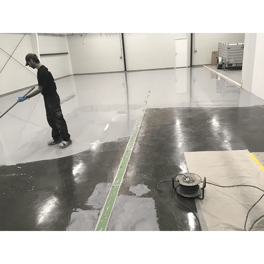 Person påfører epoxybelægning på gulv i lagerhal